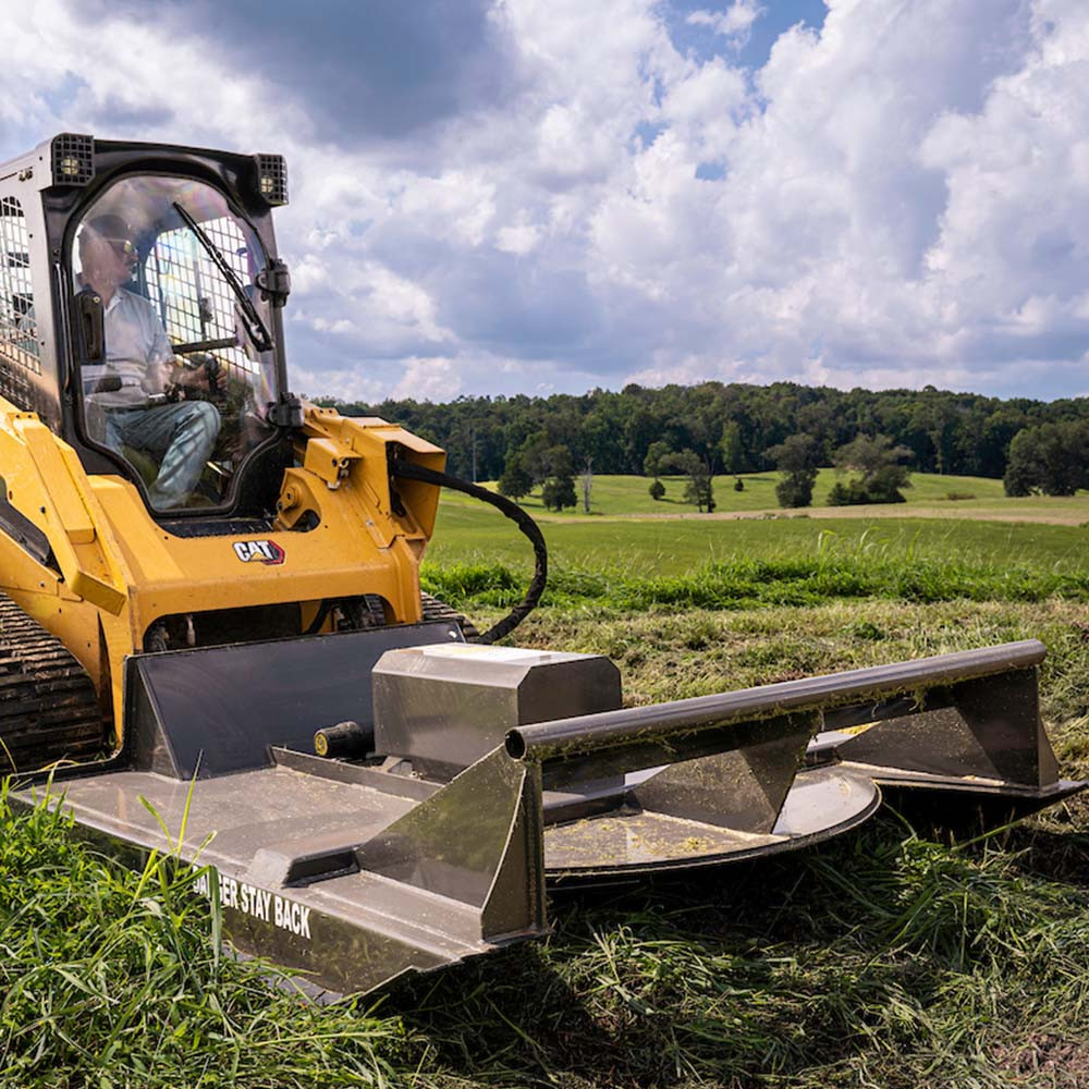 Tractor brush hogging overgrown field beside fence line on rural property